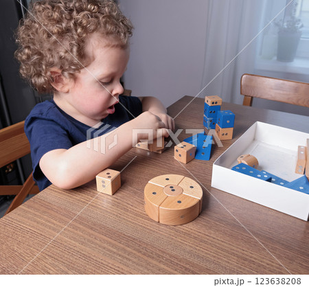 Little boy play with wooden on magnets constructor at home on table. Children and educational games. Little boy play with wooden on magnets constructor at home on table. Children and educational games. 123638208