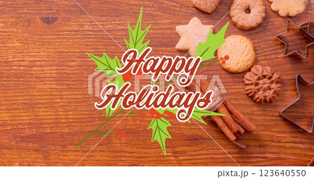 Image of happy holidays text with leaves over cinnamons, cookies and milk on wooden table 123640550