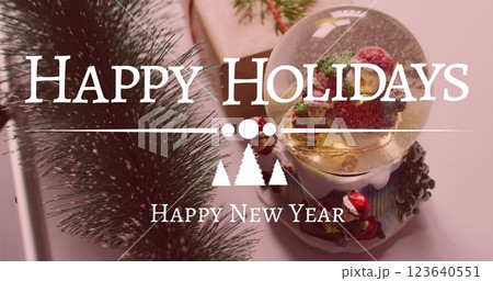 Image of christmas greetings text over christmas snow globe and decorations 123640551