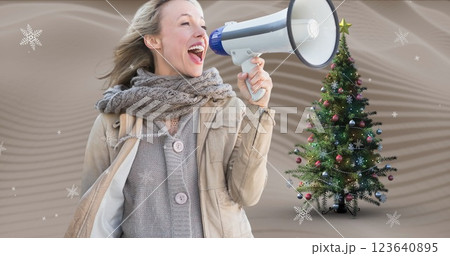 Image of caucasian woman with loudspeaker and christmas tree over snow falling 123640895