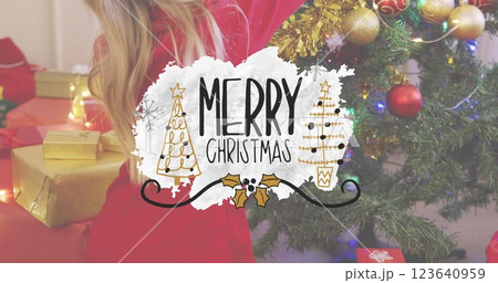 Image of merry christmas text banner against rear view of girl decorating a christmas tree Image of merry christmas text banner against rear view of girl decorating a christmas tree 123640959