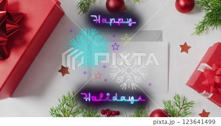 Happy holiday message written in neon lights, along with falling snowflakes 123641499