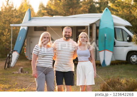 Family enjoys camping adventure near their camper van with surfboards in a natural setting during golden hour Family enjoys camping adventure near their camper van with surfboards in a natural setting during golden hour 123642268