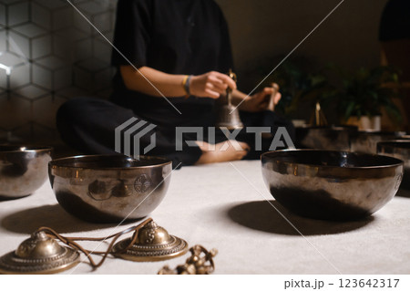 Practicing mindfulness and meditation with singing bowls in a tranquil indoor setting during a holistic wellness session Practicing mindfulness and meditation with singing bowls in a tranquil indoor setting during a holistic wellness session 123642317