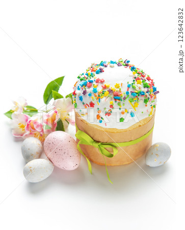 Easter cake with colorful sprinkles, decorated eggs, and spring flowers on white background 123642832
