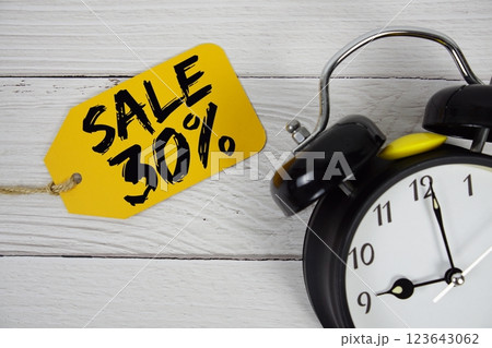 Sale 30% on price tag with alarm clock on wooden background Sale 30% on price tag with alarm clock on wooden background 123643062
