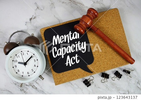 Mental Capacity Act text on speech bubble with alarm clock and wooden gavel on marble background 123643137