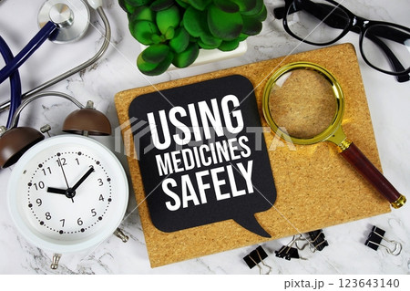 Using Medicines Safely text on speech bubble with alarm clock, magnifying glass and stethoscope on marble background 123643140