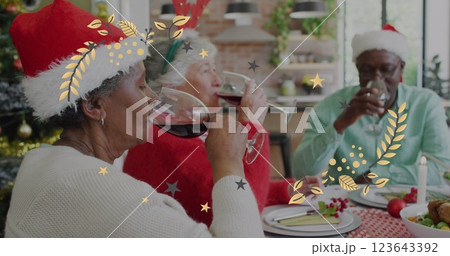 Image of christmas pattern over senior diverse friends in santa hats at christmas meal table 123643392