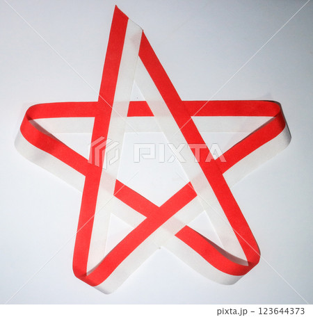 Minimalist red and white ribbon arranged in a star shape on a white background. Celebrate Indonesia independent day on 17 August, ribbon In colors of Indonesia flag red and white. 123644373