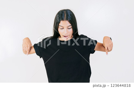Amazed girl pointing at advertising down isolated. Surprised latin girl pointing blank space down 123644818