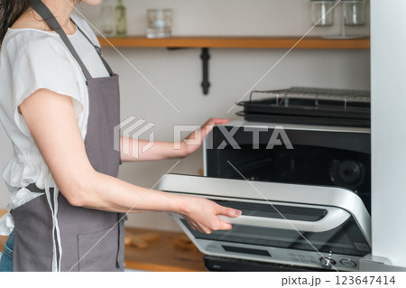 キッチンで電子レンジを使う女性（顔なし） 123647414