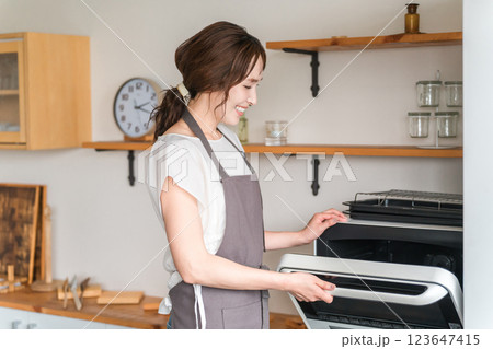 キッチンで電子レンジを使う女性（笑顔） 123647415