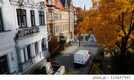 White cargo van in an old European city with autumn foliage 123647445