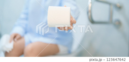 Woman holding toilet paper roll while sitting on toilet bowl. digestion, constipation, Diarrhea from food poisoning, infection, abdominal, stomachache, cystitis, Insurance, Health care and Medical 123647642