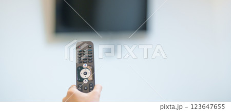 hand using remote controller press button for adjust Smart TV in modern room at home. Woman holding remote control, switch channel, searching new interesting program, Turn on or off on Television hand using remote controller press button for adjust Smart TV in modern room at home. Woman holding remote control, switch channel, searching new interesting program, Turn on or off on Television 123647655