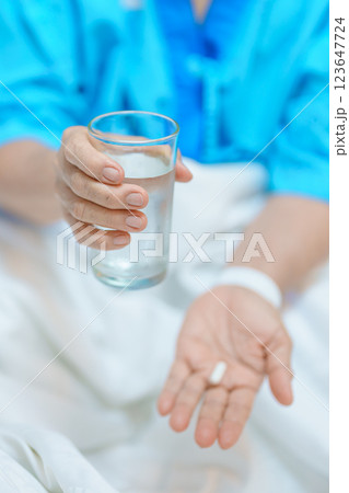 Elderly asian Patient Woman hold pill and glass of fresh water. Female Senior take medicine tablets in hospital. Influenza, Fever, illness, treatment, Insurance, Healthcare, medical and Medicine day 123647724