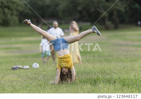 Young girl doing a cartwheel in the park while family watches 123648117
