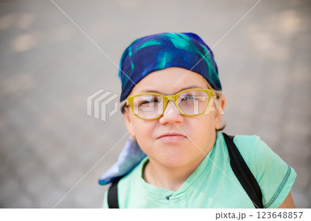 A playful small boy in glasses and a headband, dressed in a green shirt and jean shorts, laughing A playful small boy in glasses and a headband, dressed in a green shirt and jean shorts, laughing 123648857