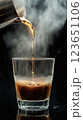 Rich coffee pouring into glass, steam rising, creating warm atmosphere 123651106