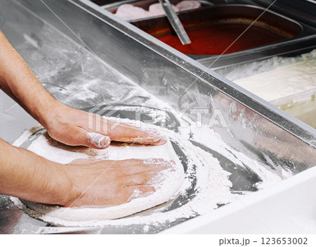 Preparing dough for pizza at a busy countertop kitchen Preparing dough for pizza at a busy countertop kitchen 123653002