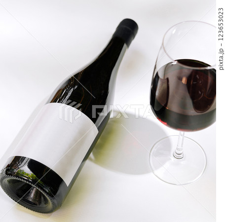 Elegant red wine bottle and glass on a white table 123653023