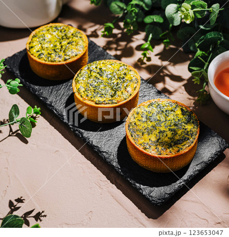 Delicious savory tarts served on a slate platter with herbs 123653047