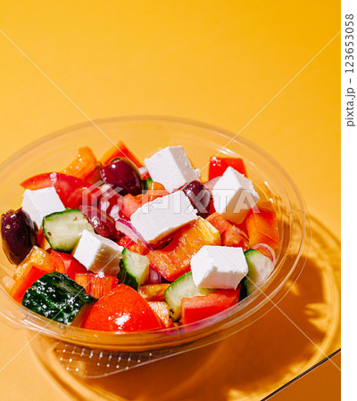 Fresh Greek salad with feta cheese and vegetables on orange background Fresh Greek salad with feta cheese and vegetables on orange background 123653058