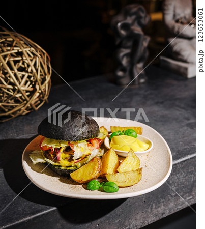Gourmet black bun burger served with golden fries and dipping sauce Gourmet black bun burger served with golden fries and dipping sauce 123653061