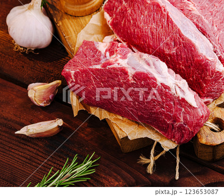 Fresh cuts of beef displayed with garlic and herbs on wooden board 123653087