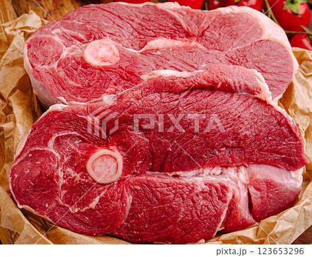 Fresh red meat cuts displayed on butcher paper with tomatoes Fresh red meat cuts displayed on butcher paper with tomatoes 123653296