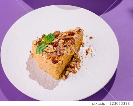 Delicious slice of cake with almonds and mint on white plate Delicious slice of cake with almonds and mint on white plate 123653358