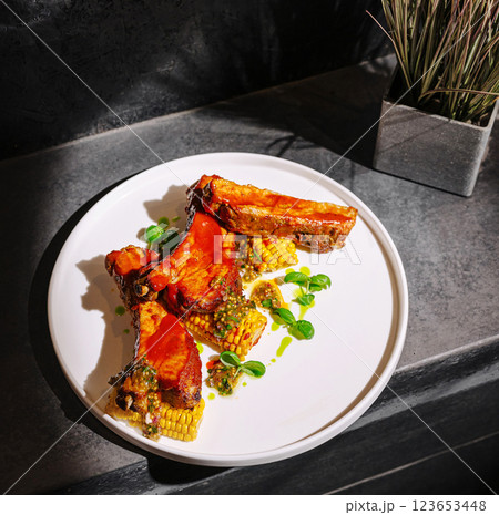 Delicious grilled ribs served with corn and herbs on a clean plate 123653448