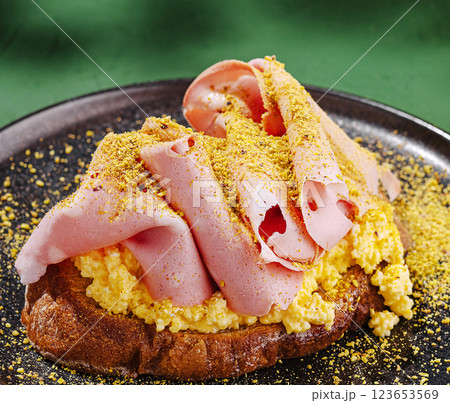 Savory breakfast dish featuring scrambled eggs and ham slices 123653569