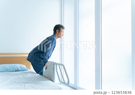 介護ベッドから立ち上がるシニア男性 介護ベッドから立ち上がるシニア男性 123653636
