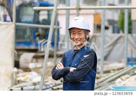 工事現場の前に笑顔で立つ職人 工事現場の前に笑顔で立つ職人 123653659