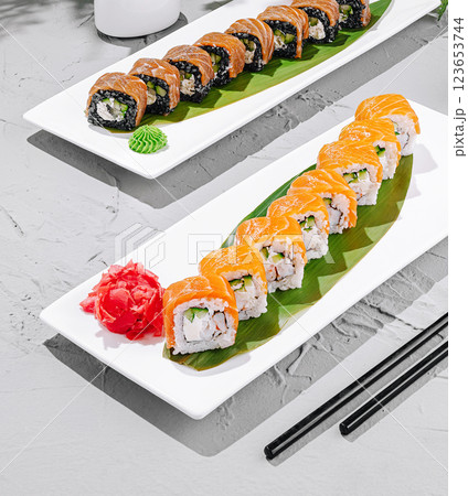 Fresh sushi rolls served on elegant plates with garnishes Fresh sushi rolls served on elegant plates with garnishes 123653744