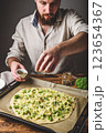 Man cooks pizza with broccoli and pesto sauce 123654367
