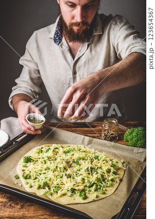 Man cooks pizza with broccoli and pesto sauce 123654367