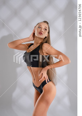 Sporty woman posing confidently in stylish black athletic wear indoors 123654706