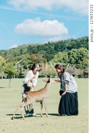 奈良公園で鹿せんべいを鹿にあげる女性（友達） 123655233