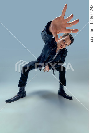 Charismatic performer reaching forward with intense gaze and dynamic posture against gradient background. Charismatic performer reaching forward with intense gaze and dynamic posture against gradient background. 123655248