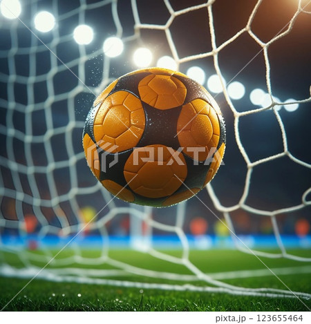 Soccer ball hitting the net in a stadium under bright lights.  123655464