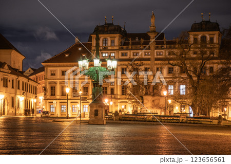 In the evening, the historic lamppost at Hradcanske Square casts a warm glow over the cobblestone streets. Surrounding buildings reflect light, enhancing the lively atmosphere of Prague. In the evening, the historic lamppost at Hradcanske Square casts a warm glow over the cobblestone streets. Surrounding buildings reflect light, enhancing the lively atmosphere of Prague. 123656561