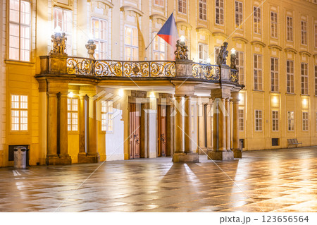 The ornate entrance to Prague Castle reveals a balcony adorned with statues, illuminated by soft lights in the evening. The tranquil courtyard reflects the beauty of the historic site. The ornate entrance to Prague Castle reveals a balcony adorned with statues, illuminated by soft lights in the evening. The tranquil courtyard reflects the beauty of the historic site. 123656564