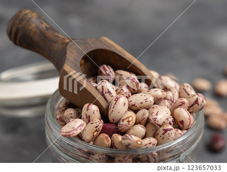 Glass jar full of dried pinto beans with scoop on gray closeup. Traditional Latin American legumes Glass jar full of dried pinto beans with scoop on gray closeup. Traditional Latin American legumes 123657033