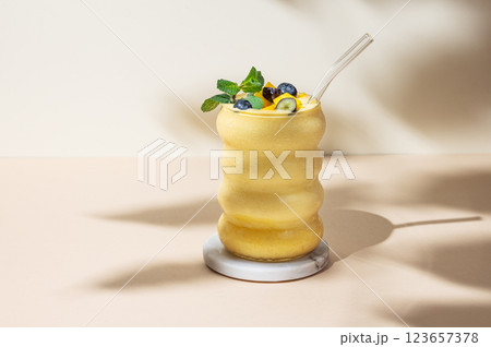 Smoothie with mango and blueberry in a glass on a yellow background with shadow. 123657378