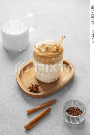 Korean whipped drink Dalgona coffee  on a woden plate on a concrete background with spice  123657396