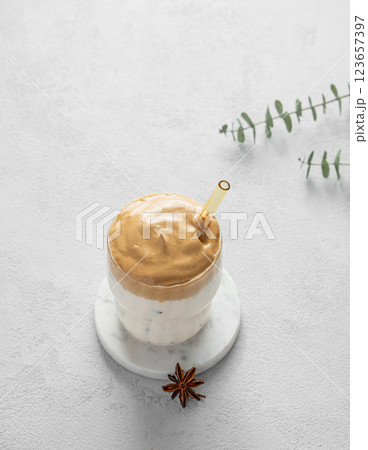 Korean whipped drink Dalgona coffee  on a marble stand on a light background with morning shadow. 123657397