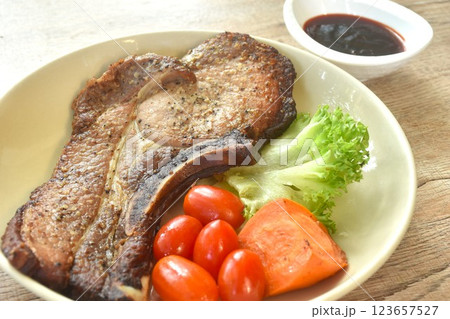 grilled black pepper pork chop steak and lettuce with tomato couple boiled carrot on plate dipping barbecue sauce in cup grilled black pepper pork chop steak and lettuce with tomato couple boiled carrot on plate dipping barbecue sauce in cup 123657527